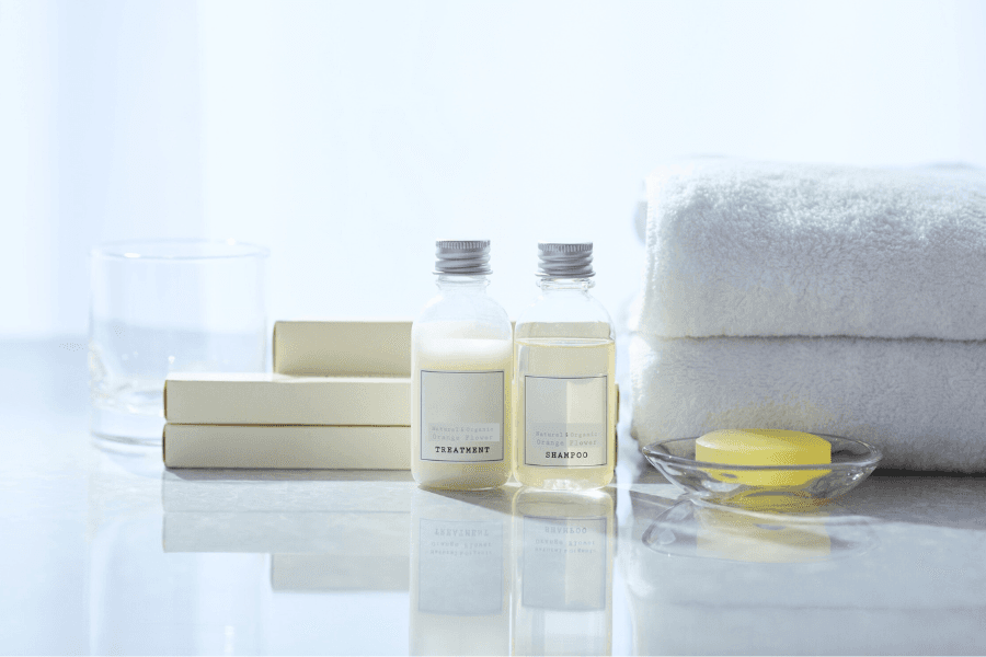 A serene bathroom setting featuring shampoo and treatment bottles, soft towels, and a soap dish.